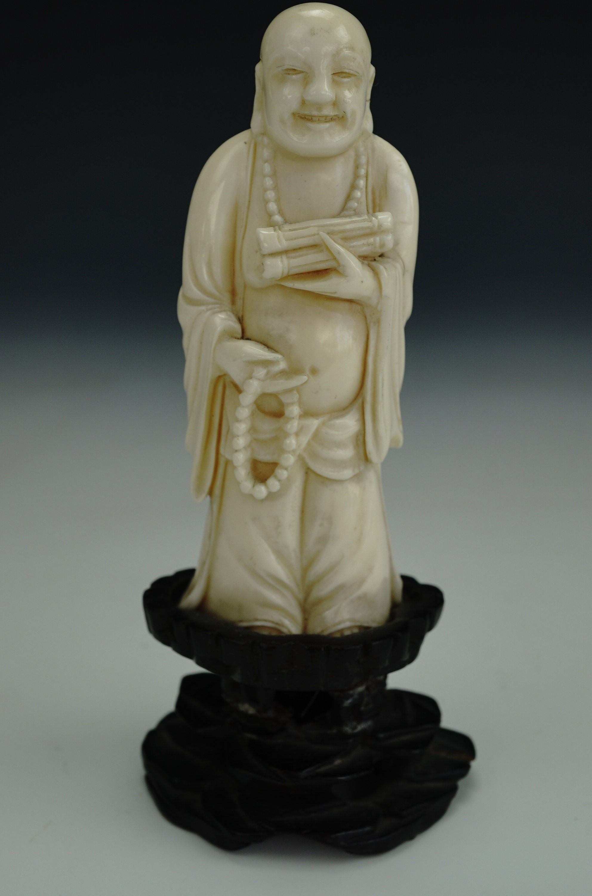 A late 19th / early 20th Century Chinese carved ivory figure of a standing Budai, in carved wooden