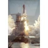 A large NASA photograph of the Space Shuttle Columbia at launch, in clip frame under glass, (not