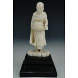 A late 19th / early 20th Century Chinese carved ivory figure of a priest, on carved ebonised plinth,
