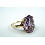A 9ct gold and amethyst cocktail ring, the oval-cut stone claw set above a strapwork gallery and