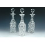 Three William IV cut glass double-spouted decanters, 30 cm