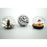 A Parlane glass paper weight together with two other glass paper weights