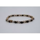 A contemporary blue stone and diamond bracelet, the oval stones of approximately 4 mm x 5 mm,