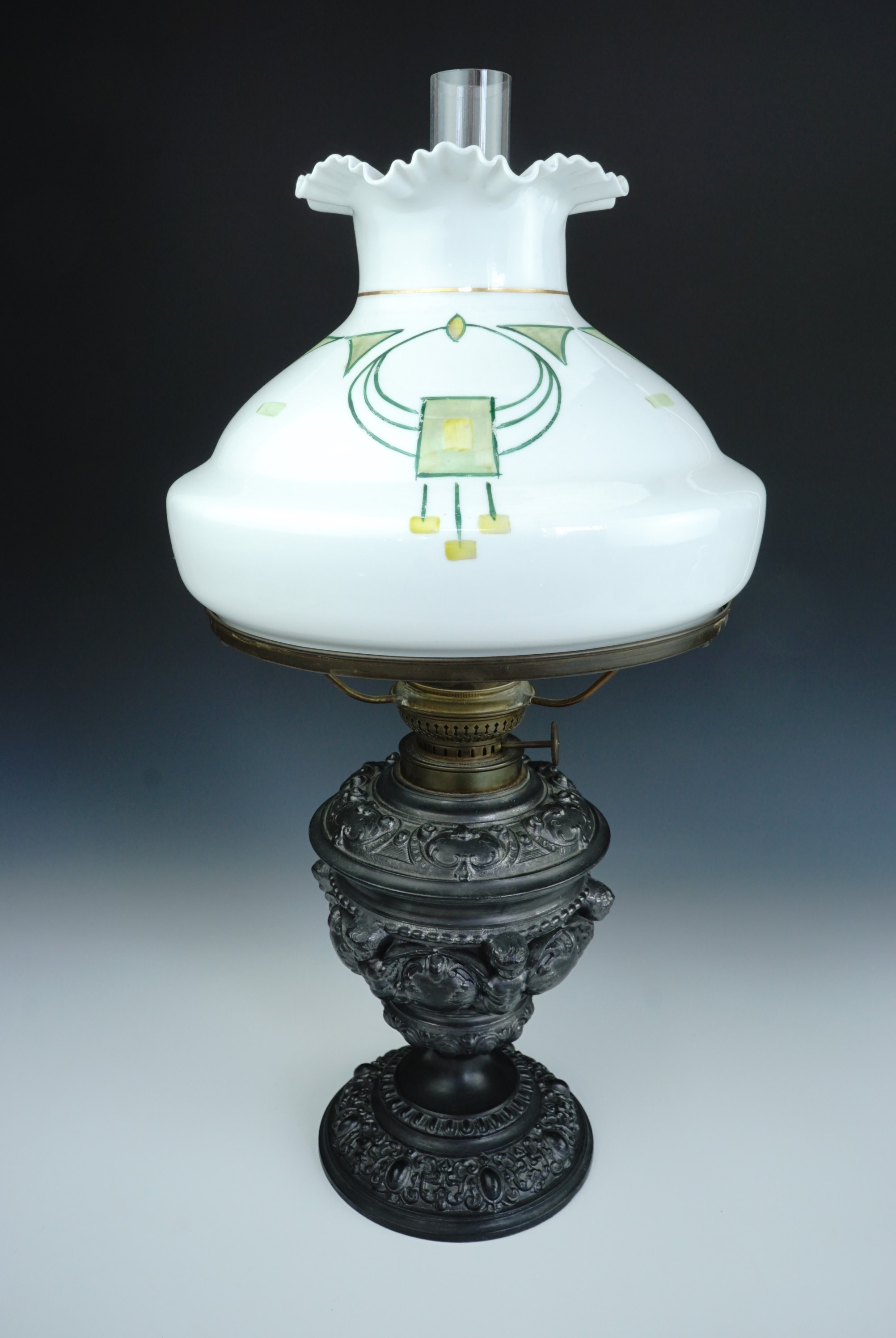 An antique German Kosmos Brenner Baroque style base metal oil lamp, the base incorporating winged