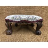 A Victorian rosewood foot stool, having an overstuffed seat and short cabriole legs with scroll