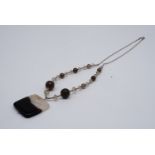 A semi-precious gemstone pendant necklace, having a square section polished drop, suspended on a