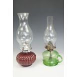 A green glass finger oil lamp together with one other, tallest 33 cm