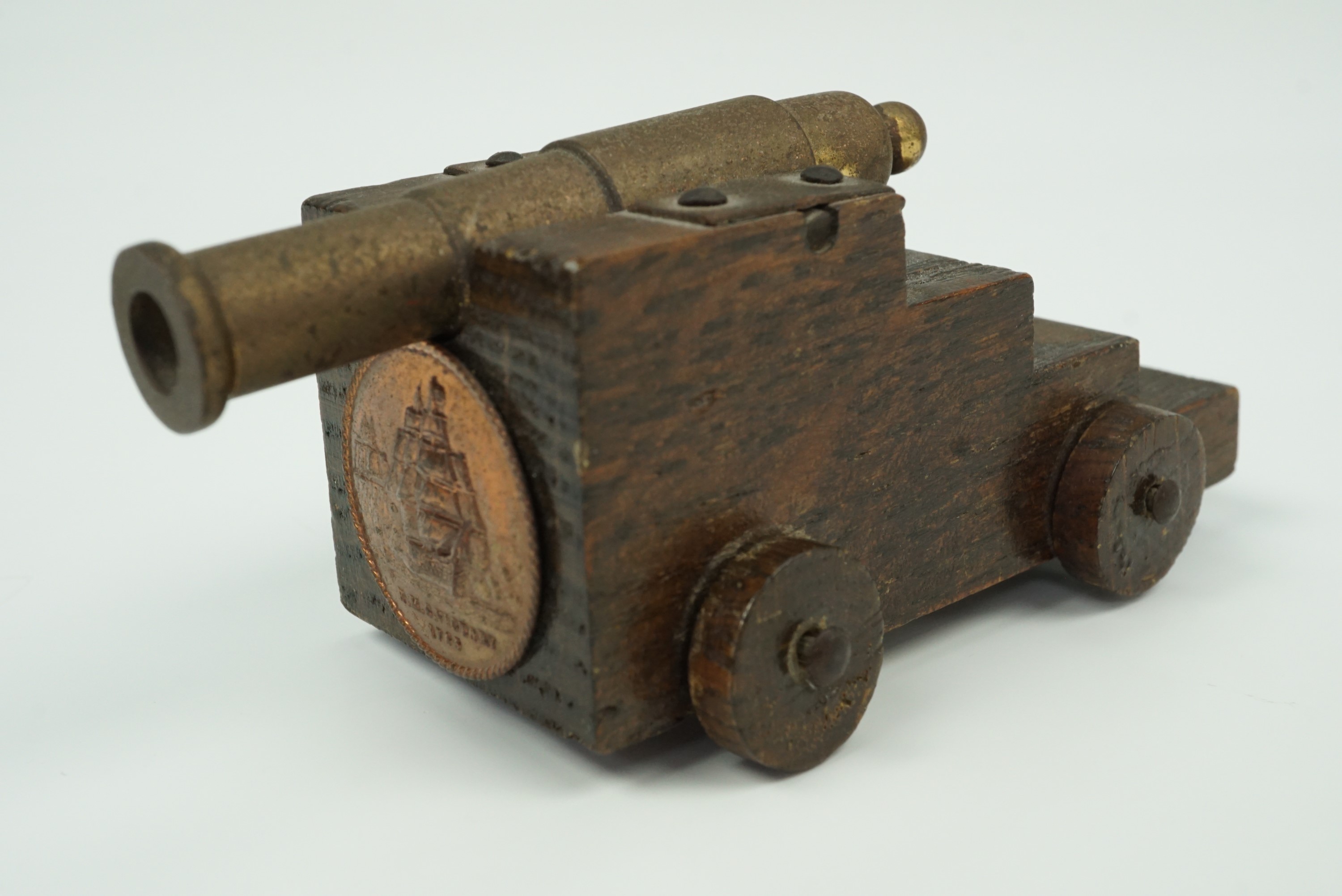A small model naval canon, its truck bearing a copper plaque with the legend "HMS Victory, 1765" and