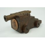 A small model naval canon, its truck bearing a copper plaque with the legend "HMS Victory, 1765" and