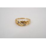 A Victorian 15 ct gold finger ring, its face a scroll sunken-set with small blue and white stones,