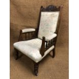 A late Victorian carved and upholstered mahogany armchair, having spindle gallery arms