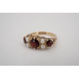 A garnet and pearl ring, comprising a central oval garnet of approximately 6 mm x 5 mm flanked by