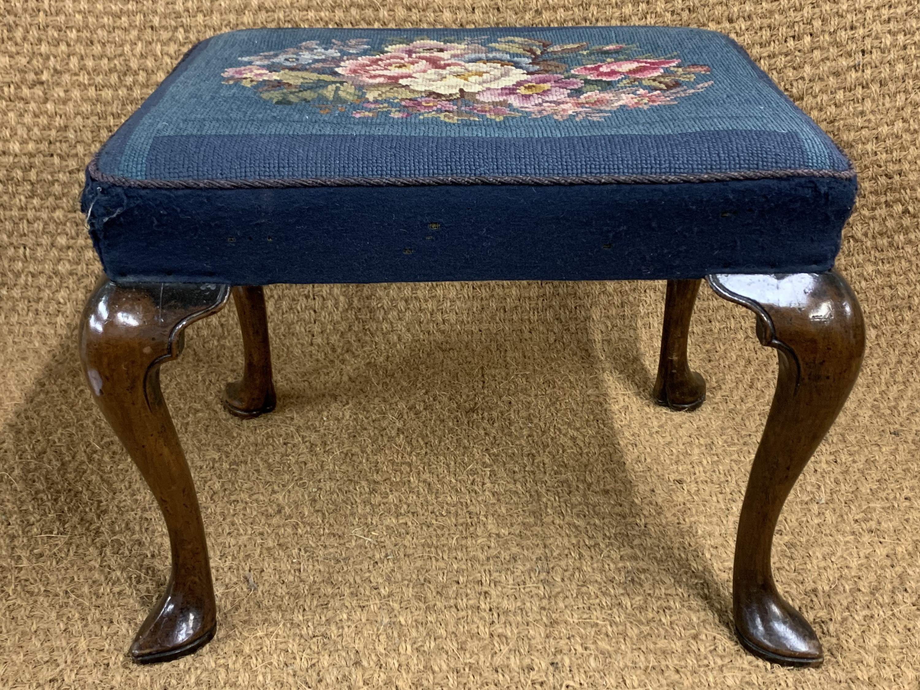 A George III walnut stool, having and overstuffed upholstered seat and cabriole legs with slipper