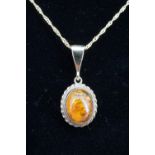 A sun-spangled amber cabochon pendant, 9 ct gold mounted and suspended on a yellow metal fine link