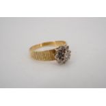 A 1970s diamond ring, comprising a flowerhead cluster of illusion set brilliants, claw set on an