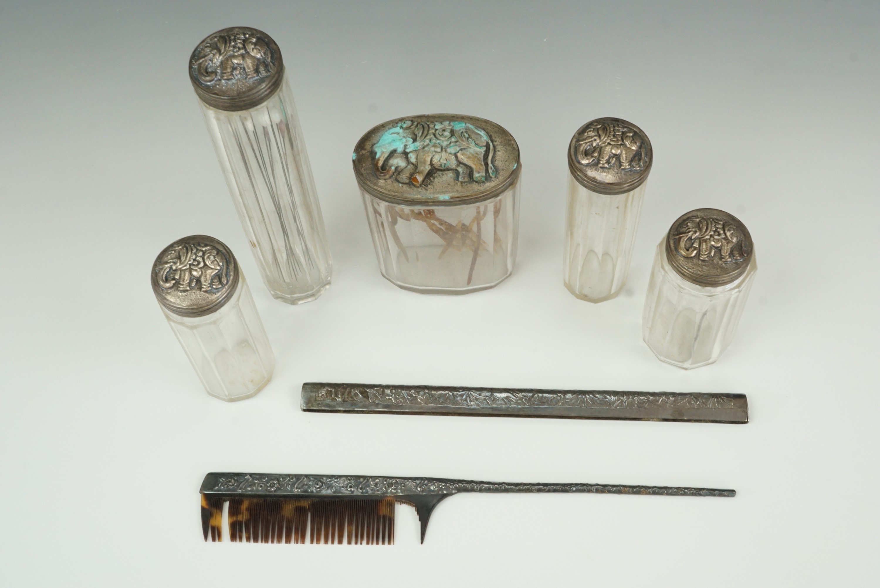 A group of Victorian cut glass toiletry jars, their white metal lids decorated in depiction of