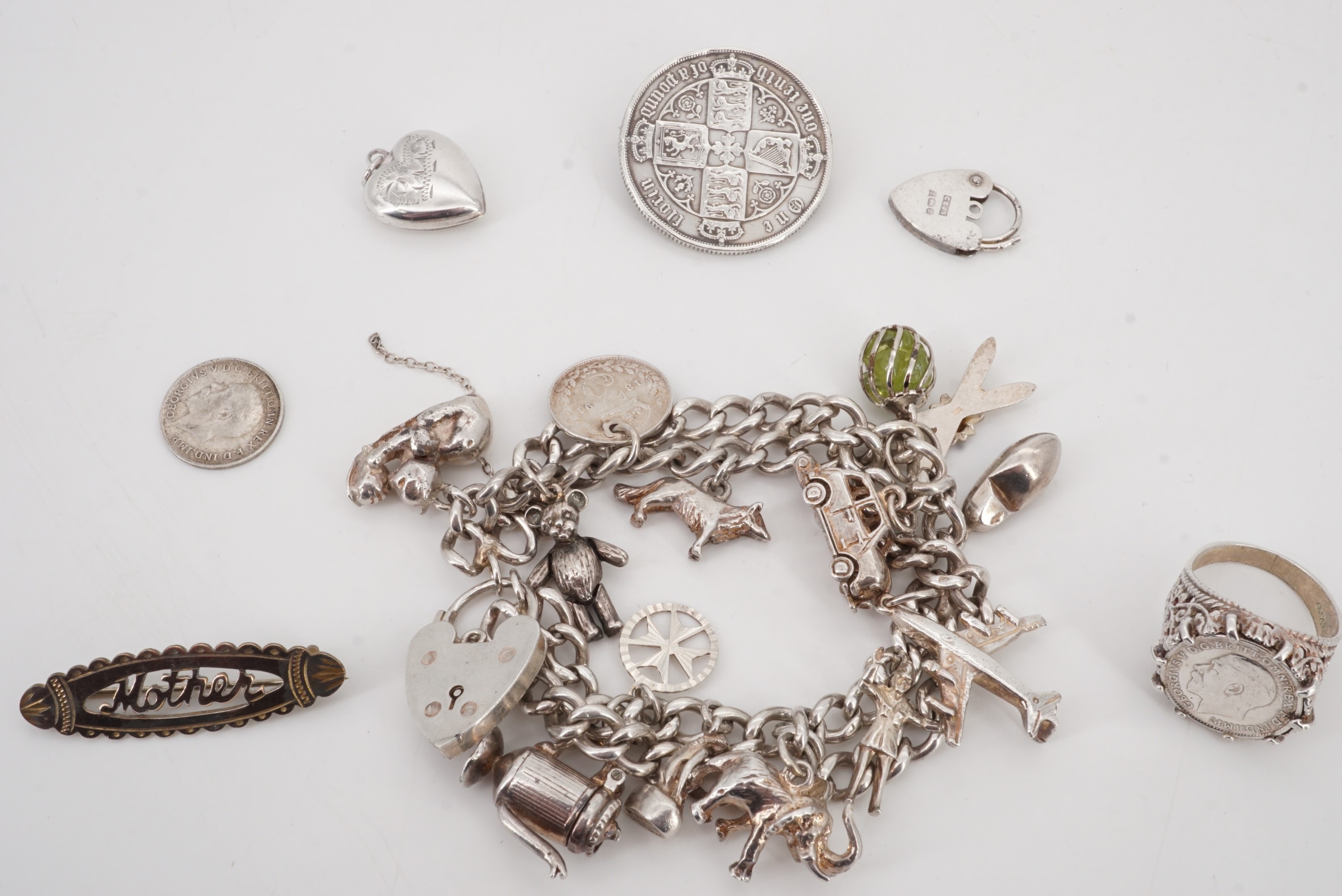 A silver charm bracelet, Victorian coin brooch, locket, "Mother" brooch and coin ring, 89 g