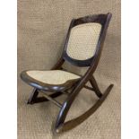 A reproduction Victorian cane-upholstered folding rocking armchair, 79 cm high