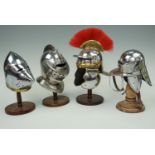 Four miniature helmets and turned wooden stands, comprising a Roman centurion's helmet, a hound's