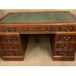 A reproduction George III pedestal desk, having a gilt-tooled leather writing surface, 137 cm x 76