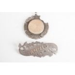 An early 20th Century silver "Annie" brooch together with a silver watch chain fob medallion, (a/f)