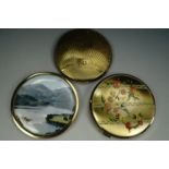 Two gilt powder compacts together with a lake scene compact