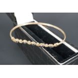 A contemporary sapphire and diamond sprung bangle, the stones bezel set between the crests of a wavy