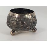 A late 19th / early 20th Century Asian white metal salt cellar, repouse worked and engraved in