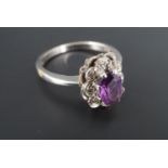 An amethyst and diamond cluster ring, comprising a central oval facet-cut amethyst of approx 7 mm
