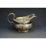 A Regency silver milk jug / sauce boat, of compressed shouldered form with gadrooned rim and foliate