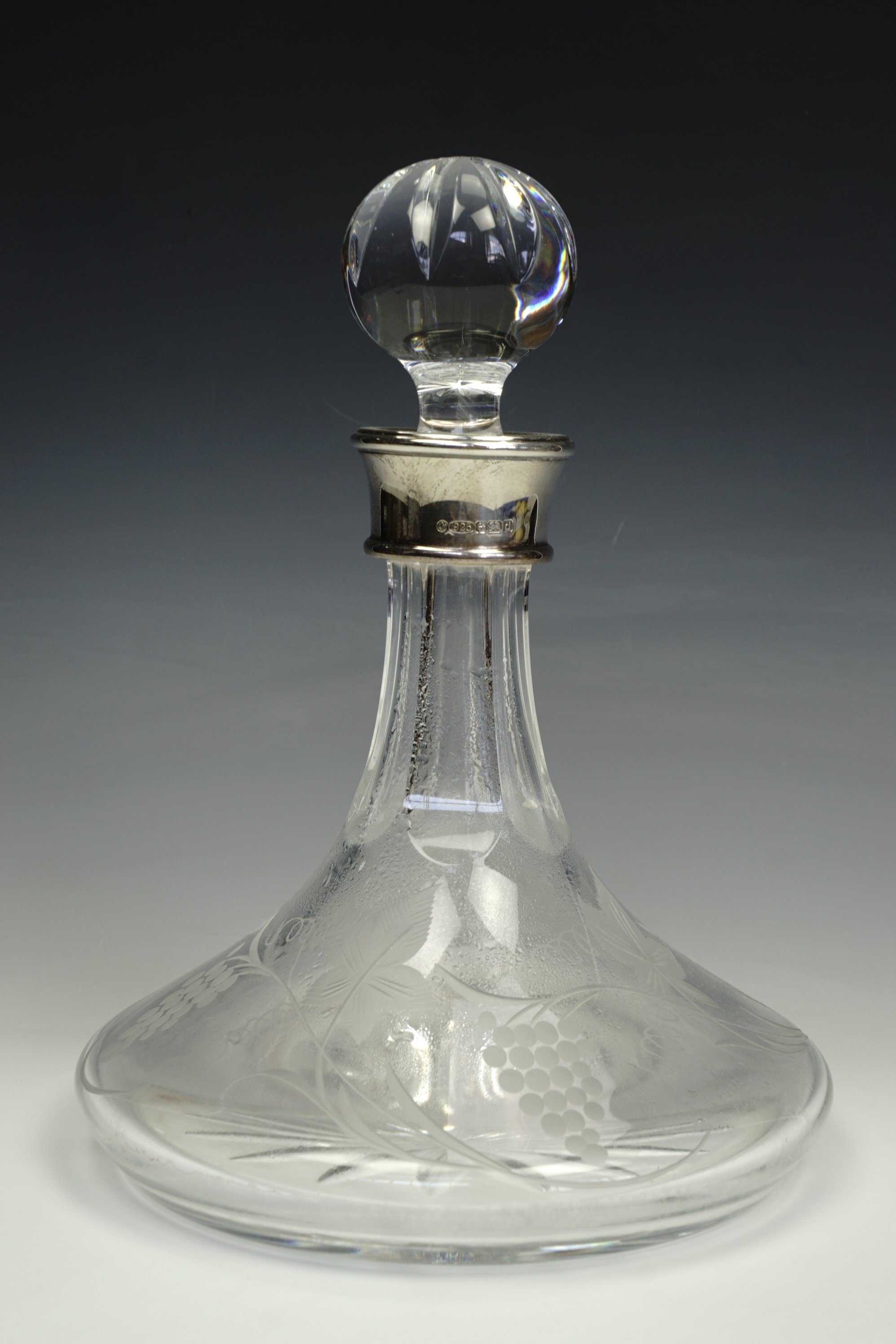 A contemporary cut glass ships decanter with foliate etchings and a silver rim; L J Millington,
