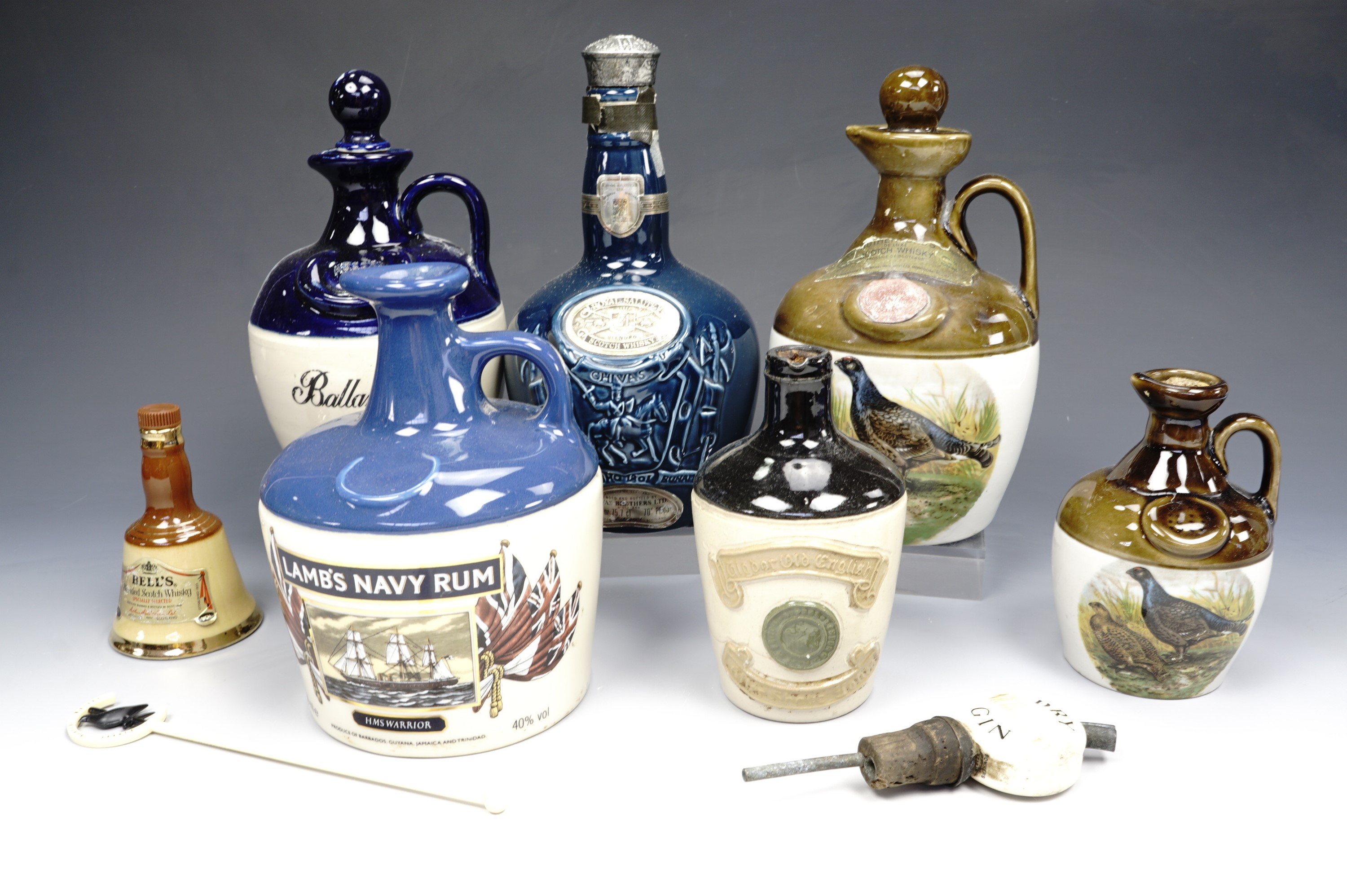 A quantity of Wade and other ceramic liquor decanters together with a bottle topper and a stirrer,