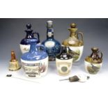 A quantity of Wade and other ceramic liquor decanters together with a bottle topper and a stirrer,