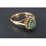 An emerald and diamond ring, the pendeloque emerald of approx 5 mm x 3 mm claw set between the