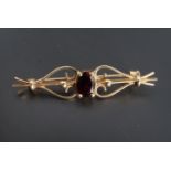 A garnet and 9 ct gold bar brooch, the oval stone of approximately 7 mm x 5 mm set between an