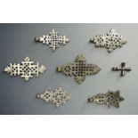 Seven white metal Ethiopian Coptic Christian crosses, cast with pierced design, largest 8 cm.