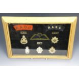 A collection of military cap and other badges, mounted and framed under glass, 25 x 35 cm