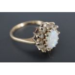 An opal and white stone cluster ring, the oval opal cabochon of approx 8 mm x 6 mm claw-set on a 9