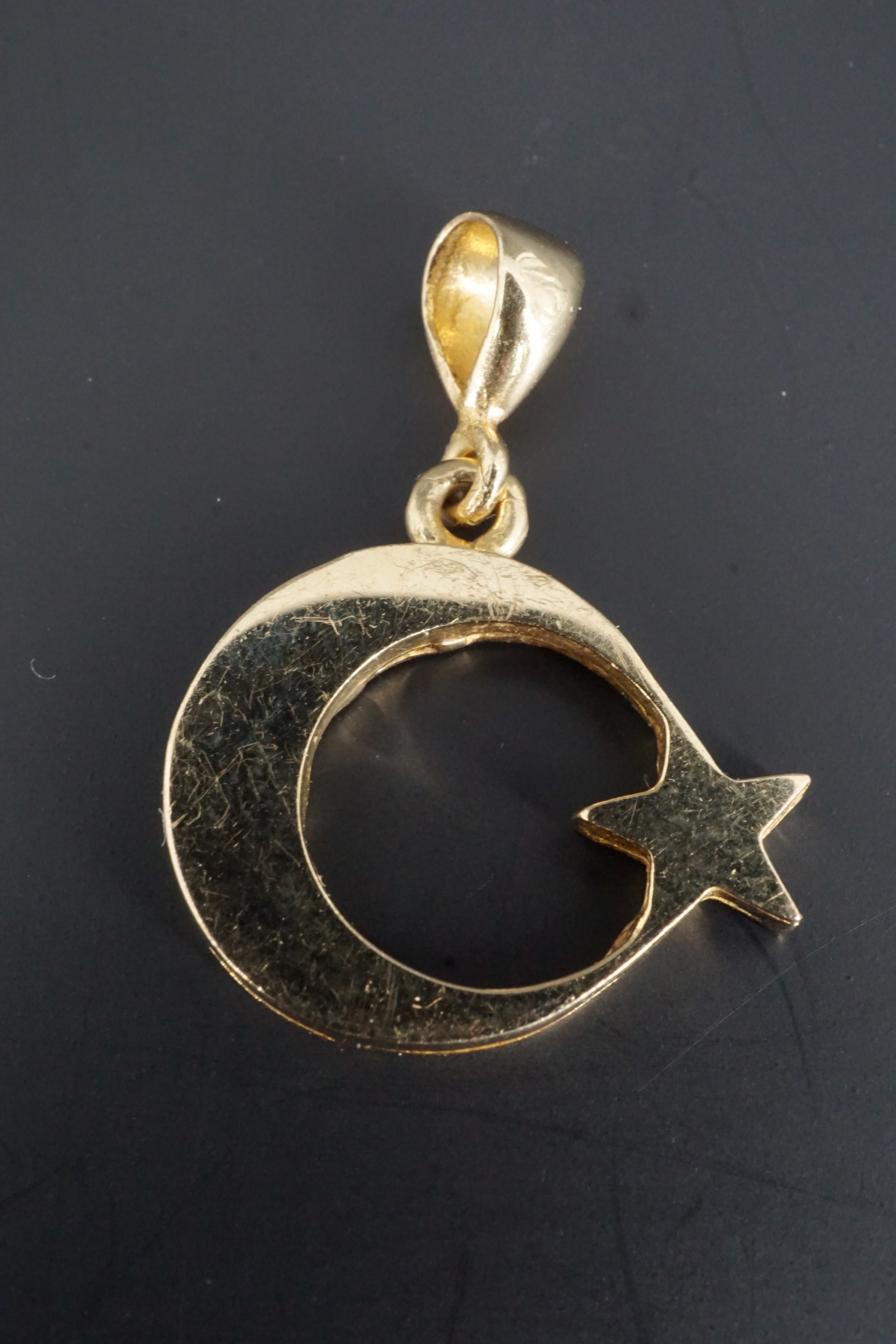 A 14 K yellow metal star and crescent pendant, 15 mm excluding suspender, 2.5 g