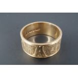 A 9 ct gold broad wedding band, its outer face engraved with a floral motif and the name 'Joan' on a