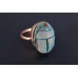 A late 19th / early 20th Century yellow metal ring, bezel-set with an Egyptian faience scarab, the