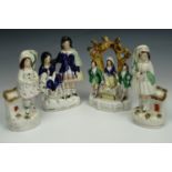 A pair of Victorian Staffordshire flat-back figurines modelled as girls holding dogs, together