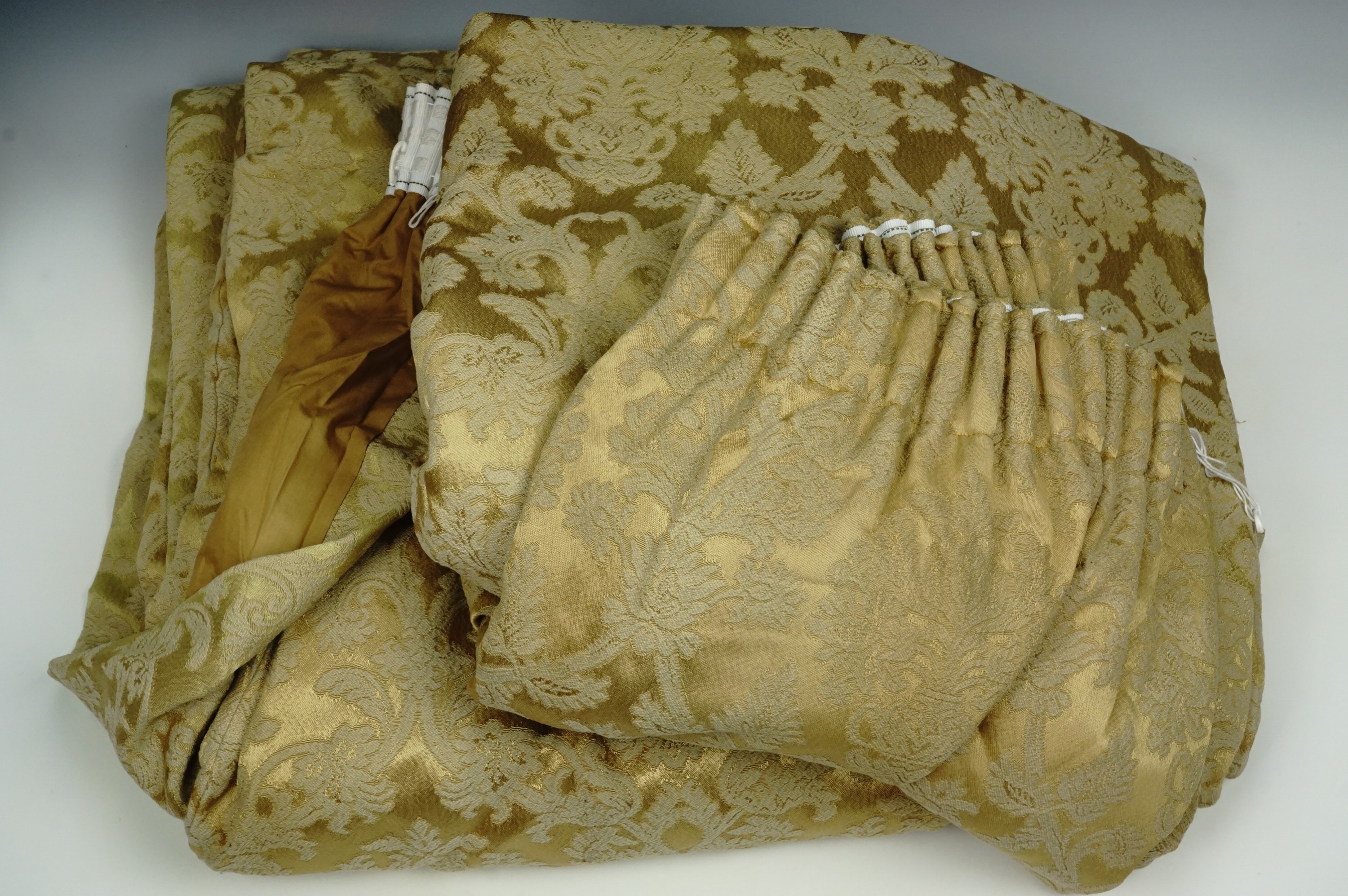 A large pair of gold damask curtains including a heavily fringed panel for a pelmet