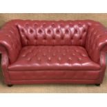 A late 20th Century red hide upholstered two-seater Chesterfield sofa, 150 cm