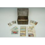 A 1935 George V silver jubilee tinplate box containing a quantity of cigarette cards and Typhoo