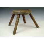 A beech and elm four legged milking stool, likely 19th century