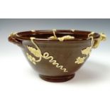 An early 20th century earthenware bowl, having a brown glaze finish with trailing grape and vine