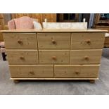 A contemporary pine effect low chest of drawers, 122 cm x 45 cm x 75 cm