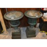 Pair of dark green patinated cast iron pedestal garden urns with detachable plinth bases, 27ins high