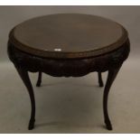 Early 20th Century carved mahogany occasional table, the circular glass inset top above a floral and